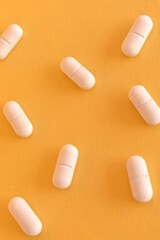 Close-up of white medical tablets on a bright yellow surface. Concept of medicine, pharmacy, and health care.