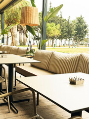 Cozy cafe interior with striped cushions and natural light overlooking green park area