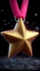 Close up of a golden star pendant with a pink ribbon against a dark bokeh background