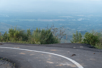 Curved mountain road with white line marking and scenic valley view in the background. Captured in daylight with natural greenery and peaceful atmosphere.