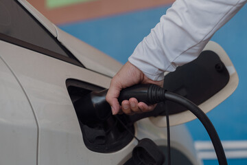 Hand is holding fast electric car charger green energy environment friendly driving vehicle station. Modern transport fuel of future. Minimal design power unit.