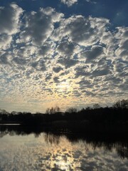Obraz premium sunset with reflection of clouds and sun in the lake in the woods