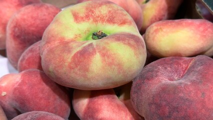 Fresh flat peaches on a wooden stall — seasonal fruits at a farmers market, symbol of natural healthy nutrition
