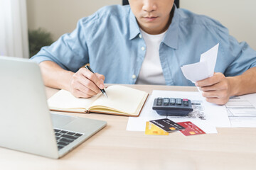 Stressed asian young businessman hand write management budget for saving cost expenses of monthly,...