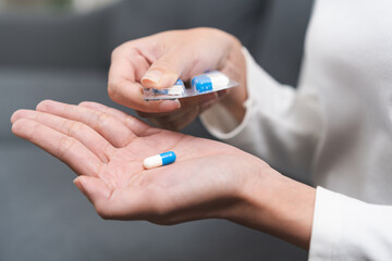 Sick ill asian young woman, girl hand taking tablet pill capsule out from blister pack, painkiller medicine from stomach pain, head ache, pain for treatment, take drug or vitamin at home, health care.