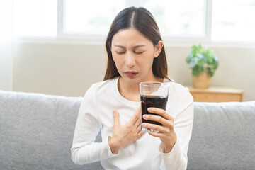 Acid reflux disease, suffer asian young woman, girl hand holding a glass of cola, have symptom...