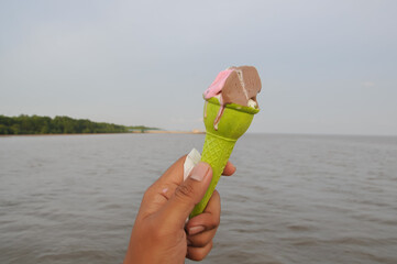 a hand of man hold ice cream with sea background