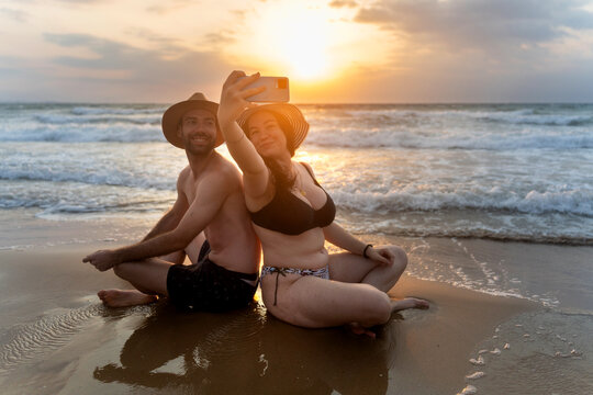 Couple taking selfie on beach at sunset