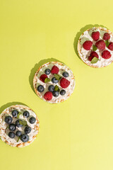 Rice cakes with different types garnish fruits, on green background. Healthy colorful food. Crispy puffed rice cakes with fruit and honey