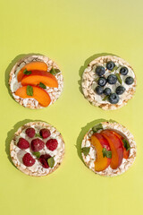 Rice cakes with different types garnish fruits, on green background. Healthy colorful food. Crispy puffed rice cakes with fruit and honey
