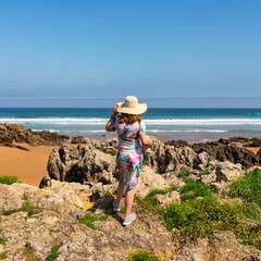 Woman with spaldas with hat on the coast Quebrada full of amazing rock formations, Cantabria, Spain.