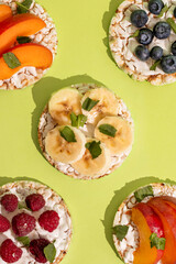 Rice cakes with different types garnish fruits, on green background. Healthy colorful food. Crispy puffed rice cakes with fruit and honey
