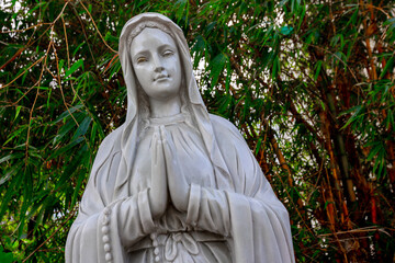 Serene stone statue of praying virgin mary with bamboo background