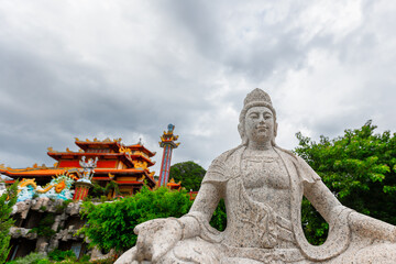 Obraz premium Statue of buddha in tranquil asian temple garden with cloudy sky