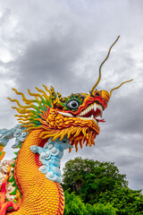 Vibrant chinese dragon statue against cloudy sky in lush greenery