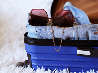 Pink women's glasses and blue suitcase, travel and tourism.