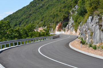 A winding panoramic road above Veli Dol curves through a lush green mountainous landscape with...
