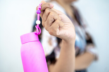 Tumbler drinking bottle in hand containing cold water isolated on white background