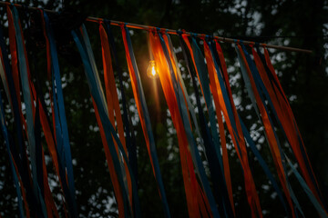 Warm string lights hang over a wooden structure decorated with yellow and blue streamers, softly...