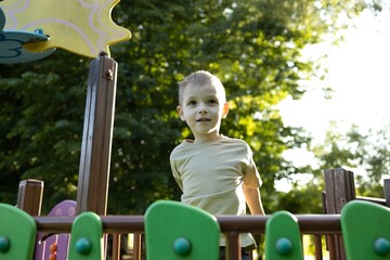 A child plays on a colorful playground structure, smiling brightly while enjoying a sunny...