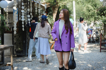 Influencer walking and smiling in a flea market wearing purple jacket and boots