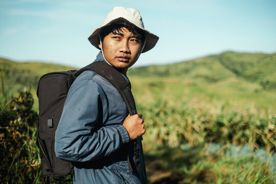 Young Asian male hiker with backpack at green valley in Indonesia