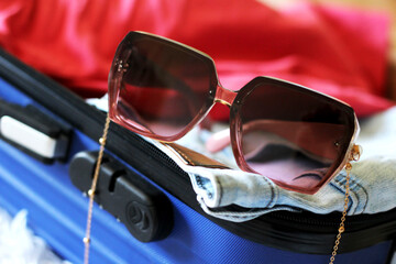Pink women's glasses and blue suitcase, travel and tourism.