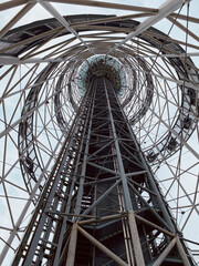 An elevator with passengers rises up in a steel tower.