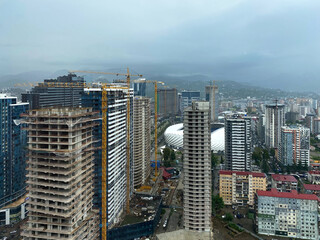 Construction several of a modern office skyscraperagainst the backdrop of grey skies and rainy weather.