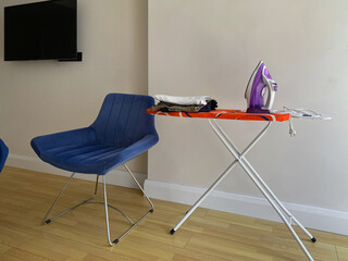 Ironing board, iron and clothes in a small budget hotel room.