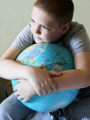 Positive boy hugging a big globe.