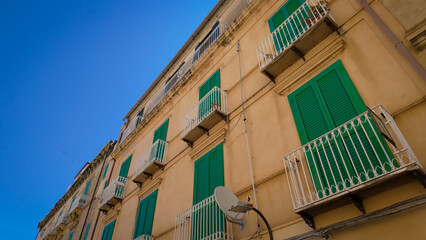 Worm s eye view of a residential building featuring green shutters and white railings, set against...