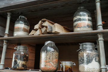  Shelves filled with various glass jars containing an assortment of dried goods like grains, beans,...
