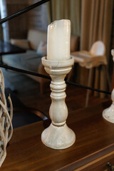 A vintage candle holder with a partially melted candle rests on a polished wooden surface, adding a...