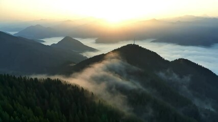 Aerial view of mountain peak at sunrise with thick morning fog drifting through valleys. The sun casts a golden glow over the ridges, creating a tranquil and serene natural landscape. Perfect for natu - Powered by Adobe