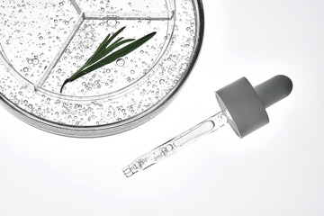 A sample of serum with a sprig of rosemary and a dropper on a white background.
