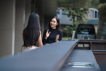 Two young businesswomen discussing a project in front of a laptop outside the office