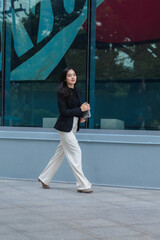Businesswoman walking outside office building holding tablet