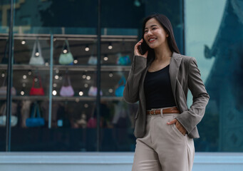 Asian businesswoman having a pleasant phone call while walking in the city