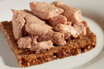 An open face cod liver sandwich on pumpernickel bread