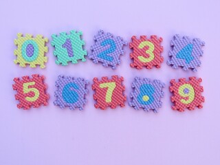 Multicolored eva foam numbers puzzle on pink background. Education background. Math background.	