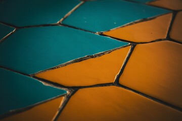 Closeup of a geometric pattern with blue and yellow tiles and dark grout lines