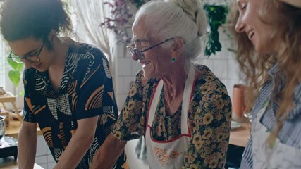 Elderly grandmother in apron smiling and talking to young grandkids as kneading dough together in home kitchen. Tilt-up shot - Powered by Adobe
