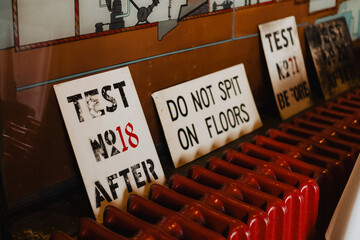 Vintage industrial metal warning signs with stenciled text leaning against red radiator, retro...