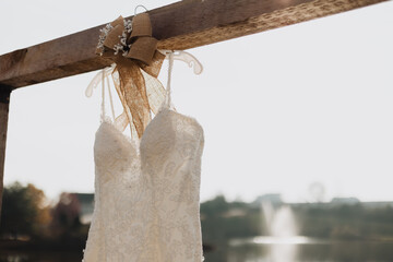 Close-up of an ivory lace wedding dress with floral embroidery and beaded details hanging on a...
