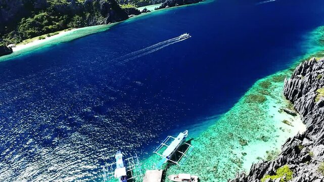 Turquoise reef and docked boats in El Nido, Palawan, Philippines from high aerial angle Aerial top view of boats docked along turquoise reef in El Nido, Palawan, Philippines with deep blue sea and cle