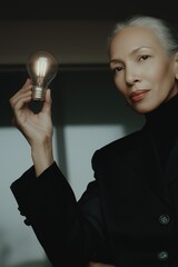 Mature caucasian female holding light bulb innovation concept