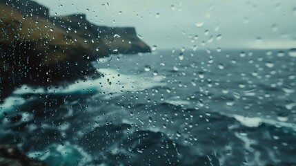 Raindrops on glass overlooking rocky cliffs and ocean waves on a cloudy day seascape view