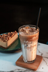 Iced Latte with Layered Milk and Espresso in Tall Glass. Blurred nut cake slice in background. Ideal for cafes, menus, websites, and social media.