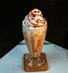 Chocolate Milkshake with Whipped Cream and Caramel Drizzle in Tall Glass. Isolated on marble table with dark background. Ideal for drink menus, advertising, and cafe branding.